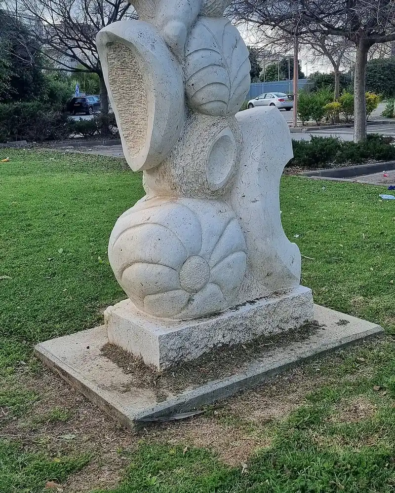 A white stone sculpture by Aviva Berger on a lawn in HaPrachim