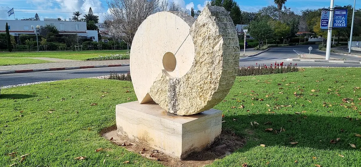 A round stone sculpture by Tanya Preminger on a lawn in Re'ut